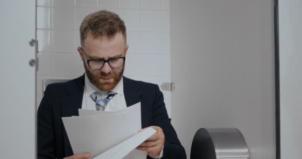 Close up of businessman readind in toilet. - Materiał filmowy, wideo