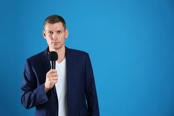 Male journalist with microphone on blue background. Space for text - Valokuva, kuva