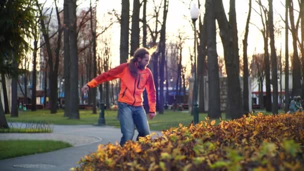 Ein professioneller männlicher Roller tanzt in den letzten Herbsttagen in Zeitlupe auf Rollerblades in einem gemütlichen Stadtpark. Idee von Outdoor-Aktivitäten und einem gesunden Lebensstil. - Filmmaterial, Video