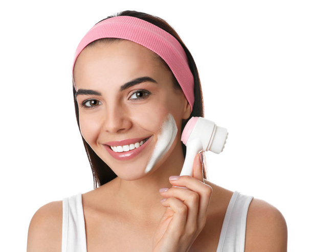 Young woman using facial cleansing brush on white background. Washing accessory - Foto, imagen