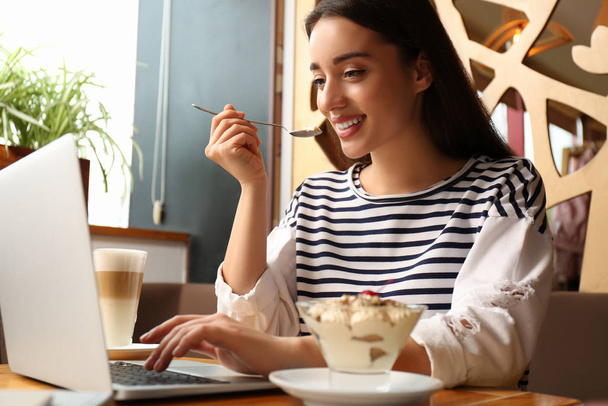 Jeune blogueur avec ordinateur portable manger dessert dans un café
 - Photo, image