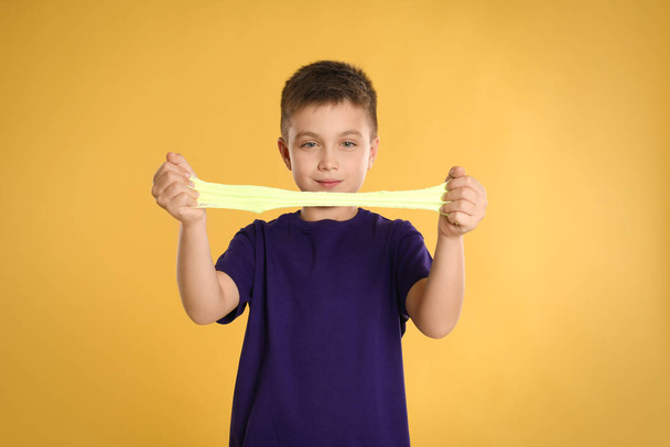 Little boy with slime on yellow background - Fotó, kép