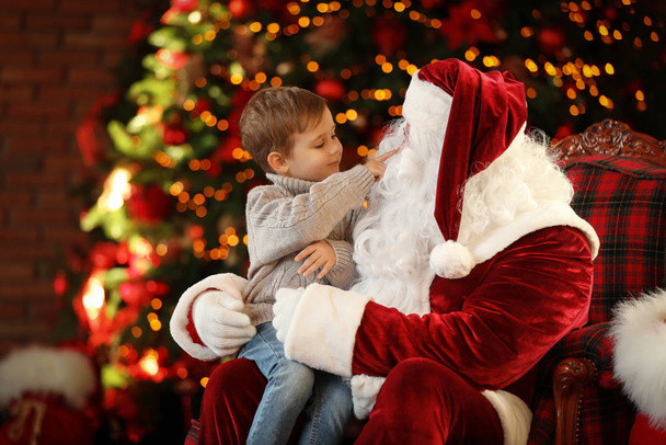 Санта-Клаус и маленький мальчик возле рождественской елки в помещении
 - Фото, изображение