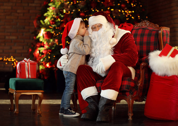 Santa Claus and little boy near Christmas tree indoors - Foto, Imagen