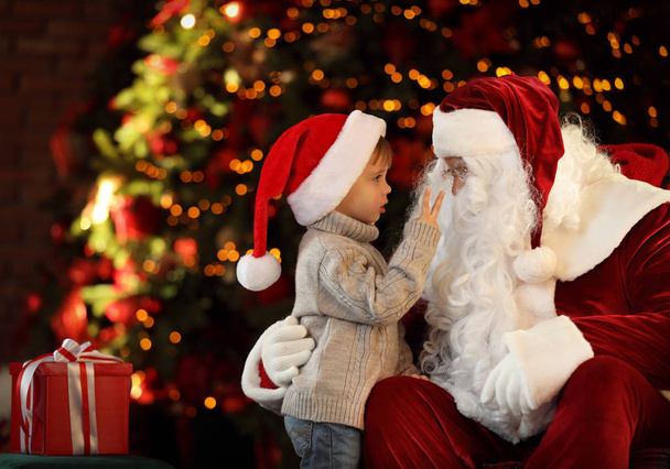 Joulupukki ja pieni poika lähellä joulukuusi sisätiloissa
 - Valokuva, kuva