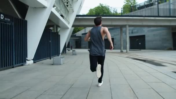 Kentsel caddede koşan sporcunun arka görüntüsü. Sporcu adam dışarıda koşuyor.. - Video, Çekim