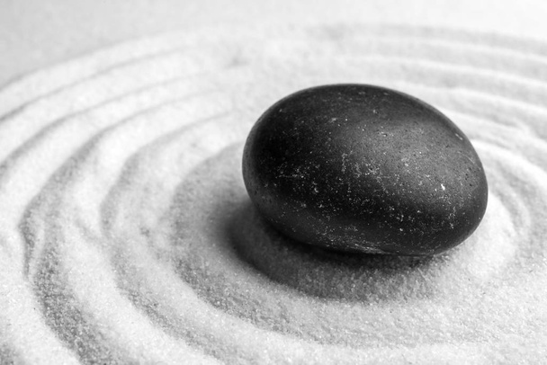 Black stone on sand with pattern. Zen, meditation, harmony - Photo, Image