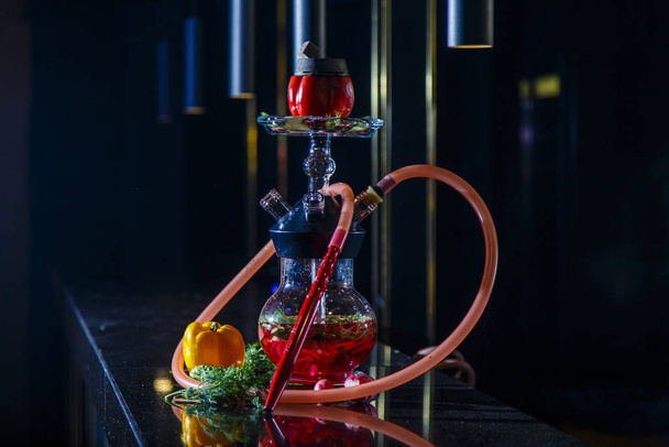 Hookah on vegetables. Hookah with a round transparent flask, which contains chopped vegetables: pepper, cucumber, radishes, herbs. Lots of smoke. - Foto, Imagen