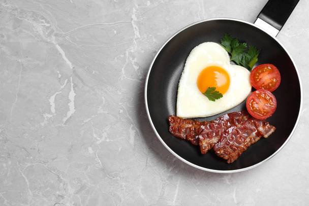 Tasty breakfast with heart shaped fried egg on grey table, top v - Foto, afbeelding