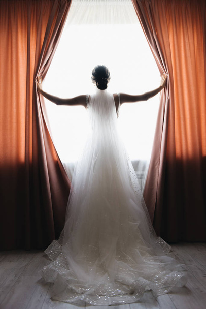 Bride and groom are standing against the window looking outside - Foto, Imagen