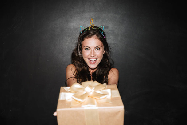 Image of brunette happy woman holding gift box and smiling - Foto, immagini