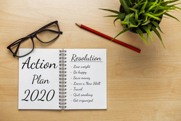 Business office desk with notebook written in handwriting about plan listing of new year goals and resolutions setting. - Photo, Image