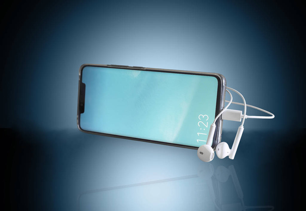 Smartphone and headphones on a blue background. - Фото, изображение