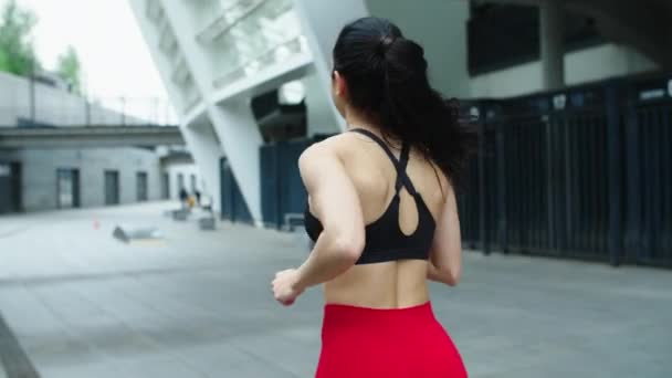 Athlete woman running outdoor. Back view of sporty girl jogging on urban street. - Video