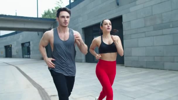 Para fitness biegająca razem po miejskiej ulicy. Prowadzenie szkolenia sportowego dla rodzin - Materiał filmowy, wideo
