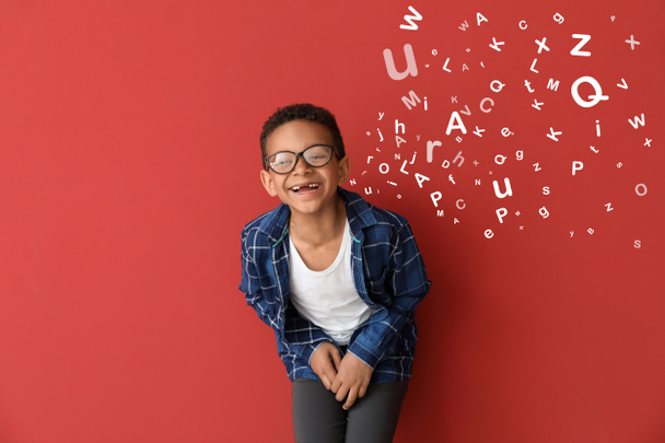 Kahkahalar atan Afro-Amerikalı küçük bir çocuk ve ağzından renkli arka planda harfler çıkıyor. - Fotoğraf, Görsel