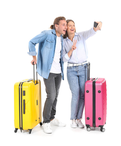 Young couple with suitcases taking selfie on white background - Foto, Imagem