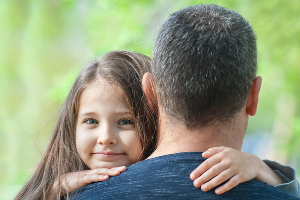 Retrato de una linda niña sostenida en brazos paternos. Familia feliz
 - Foto, imagen