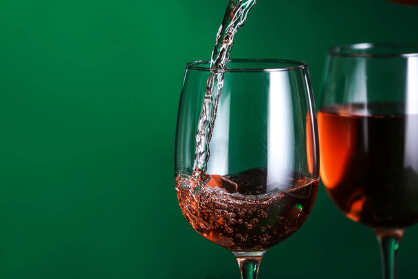 Pouring of tasty wine into against color background - Photo, Image