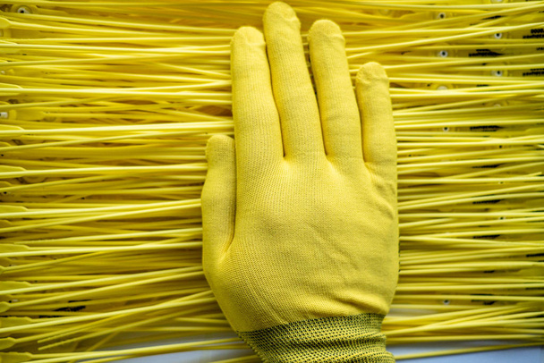 Auf dem gelben Hintergrund aus Plastikfäden ist eine Hand in einem gelben Handschuh - Foto, Bild