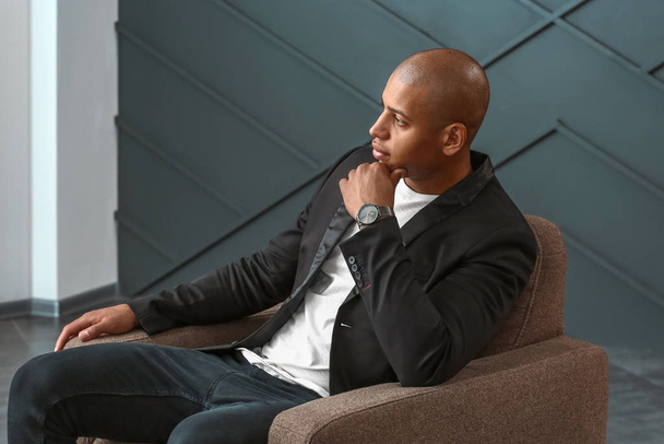 Stylish African-American man sitting in armchair indoors - Fotoğraf, Görsel