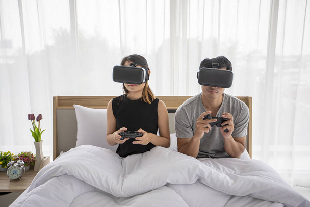 アジアのカップルの恋人はベッドルームでビデオゲームを楽しむ、アジア  - 写真・画像