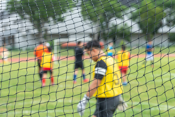 Seçici odaklanma. Bulanık arka plan. Futbol kalesinin arka planı ve Asyalı erkek kaleci ve diğer oyuncular. - Fotoğraf, Görsel