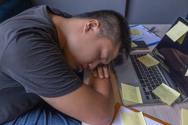 Giovane freelance addormentarsi sul computer portatile sul posto di lavoro non organizzato
 - Foto, immagini