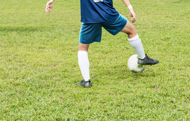 Нижний вид сзади неизвестного футболиста в синем на футбольном поле. Он останавливает мяч правой ногой.
. - Фото, изображение