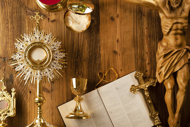Tema da Igreja Católica Romana. A Cruz, a Bíblia Sagrada, o monstrance, o rosário e o cálice dourado na mesa de madeira rústica
 - Foto, Imagem