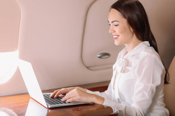 Businesswoman with laptop on board the modern private airplane - Foto, afbeelding