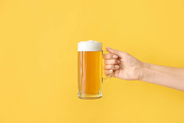 Hand with mug of beer on color background - Foto, Imagen