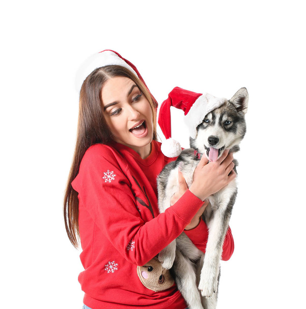 Cute woman with funny husky puppy in Santa Claus hats on white background - Fotó, kép
