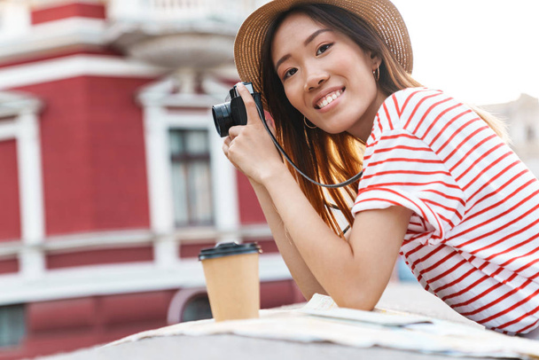 Asian woman walking outdoors with camera drinking coffee. - Foto, Imagen