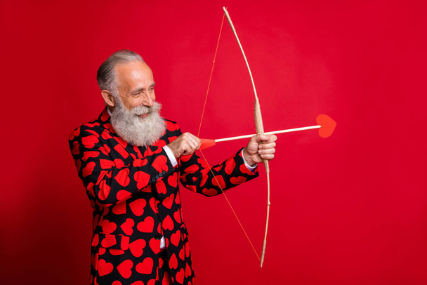 Portrait of his he nice attractive cheery white-haired guy shooting arrows wedding match making soulmate date service passion desire isolated on bright vivid shine vibrant red color background - Foto, immagini
