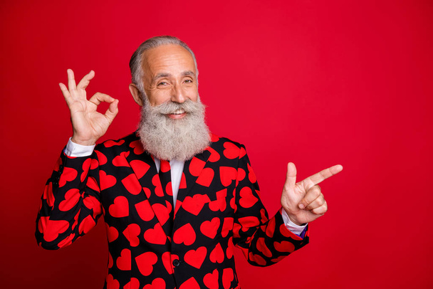 Photo of funky aged handsome man amour direct finger empty space show okey symbol advising novelty wear hipster hearts pattern suit blazer tie isolated vivid color background - Фото, изображение