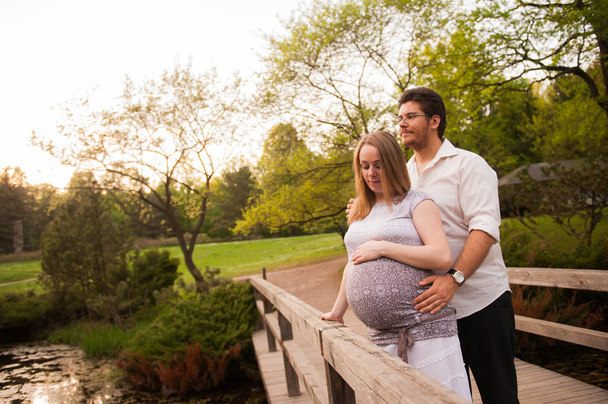 A man with a pregnant woman on the bridge in the park - Foto, Imagen