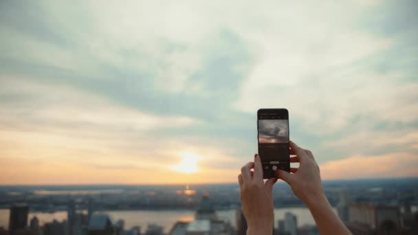 Női kéz egy telefonnal fotózás naplemente - Felvétel, videó