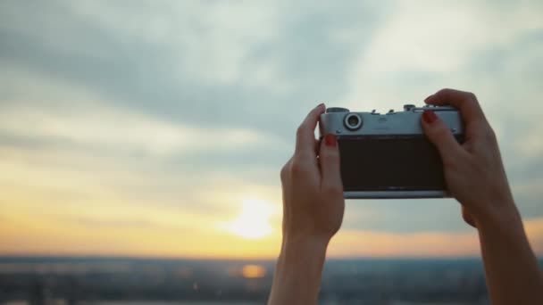 Manos femeninas con una cámara retro tomando fotos del atardecer
 - Imágenes, Vídeo