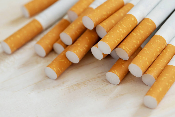 obraz kilku produkowanych komercyjnie papierosów stos na białym drewnianym tle. lub koncepcji kampanii dla niepalących, wzór tytoniu widok z góry. - Zdjęcie, obraz