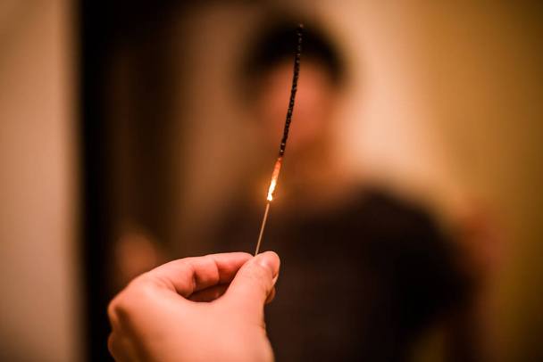 In a female hand a burnt, burning sparkler - fire hazard during celebration - 写真・画像