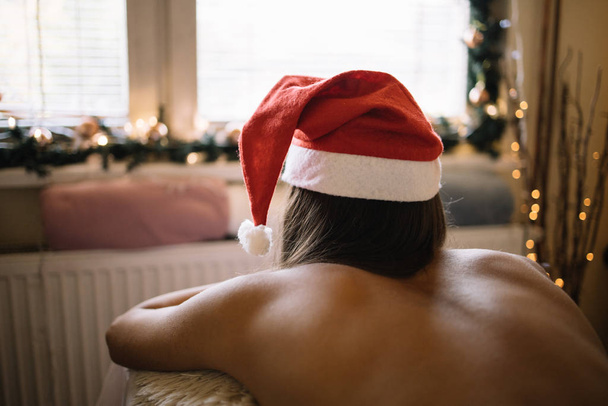 junges Mädchen mit Weihnachtsmütze auf Massagetisch liegend - Foto, Bild