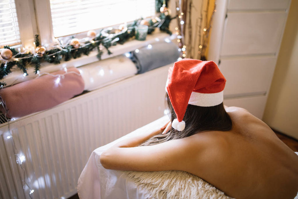 Woman with Santa hat laying on massage bed - 写真・画像