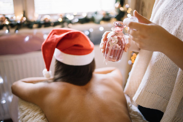 Woman with Santa hat ready for massage with oil - Zdjęcie, obraz