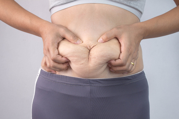 Κοντινό πλάνο του χεριού της γυναίκας τσίμπημα υπερβολικό λίπος στην κοιλιά απομονωμένο o - Φωτογραφία, εικόνα