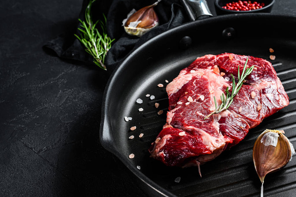 Marbled beef steak in a frying pan. Organic farm meat. Black background. Space for text - Foto, afbeelding