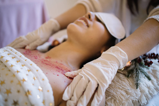 SPA therapists hands applying scrub on womans chest - Photo, Image