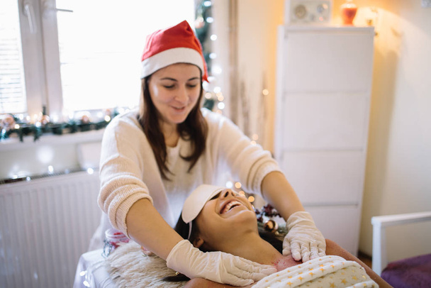 Therapeutin mit Weihnachtsmütze schrubbt Frauenbrust - Foto, Bild