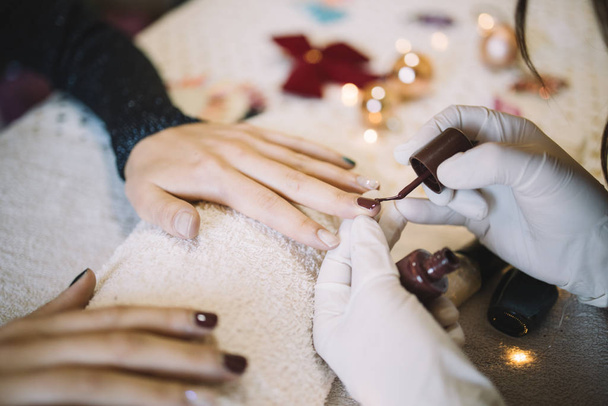Hands of a manicurist applying nail polish on womans fingernails - Fotoğraf, Görsel