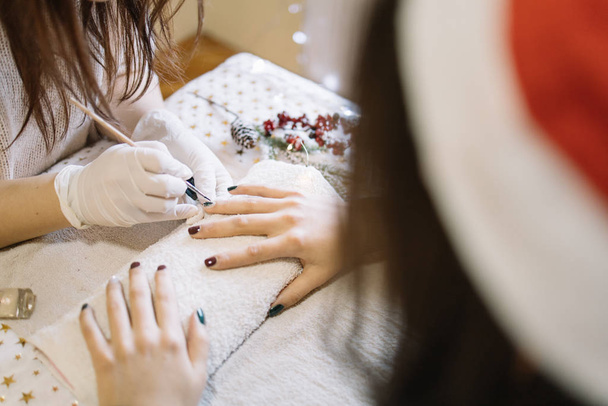 Client with Santa hat doing manicure at nail salon - 写真・画像